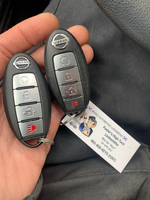 Two Nissan push-to-start fobs in an open hand with a Foster's High Tech Locksmiths card